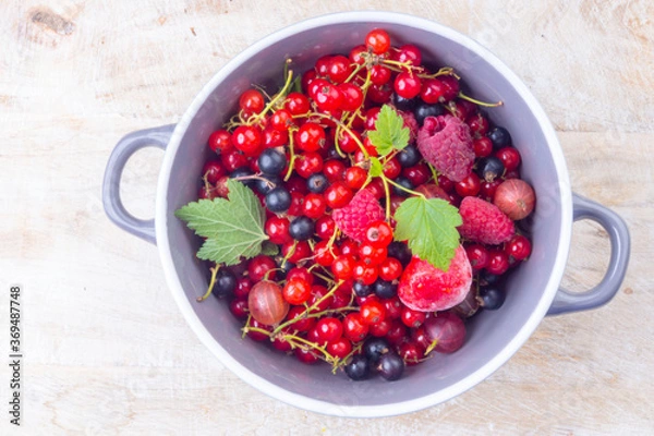 Fototapeta mixed berries in a bowl on wooden table