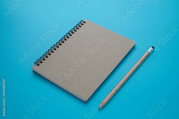 Obraz Top view above of brown spiral notebook and pencil isolated on blue background for design a mockup. 