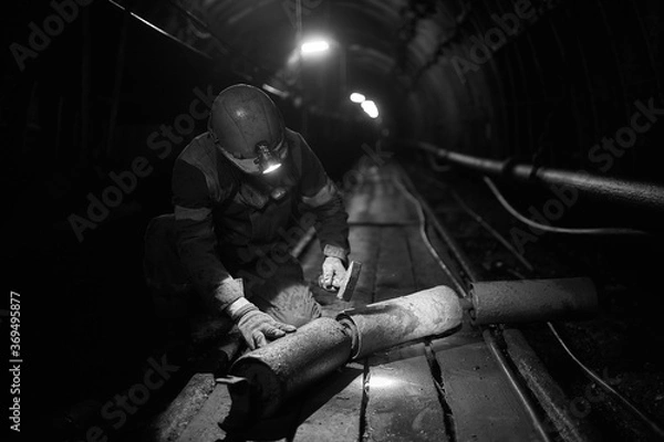 Fototapeta Silhouette of a working miner in a mine