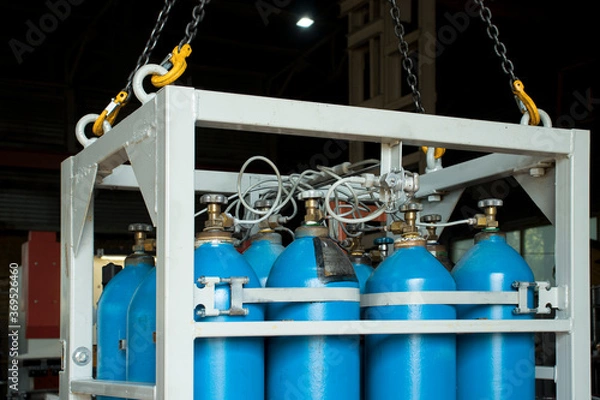 Fototapeta Oxygen cylinders in a cassette suspended from the hooks of a crane in the workshop of the plant.