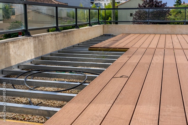 Fototapeta  Construction of a wooden terrace on a balcony. A new wooden, timber deck being constructed. City background. 