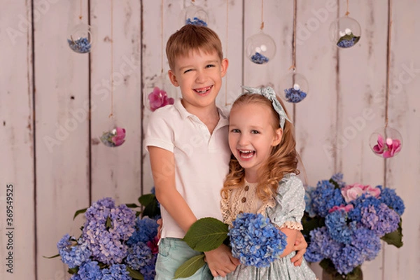 Obraz Happy baby boy and girl in studio on white background with pink and blue hydrangea flowers