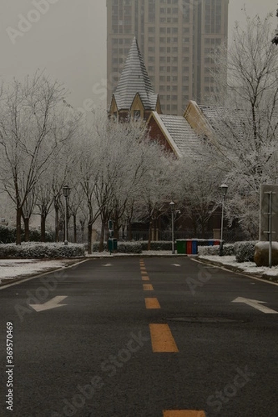 Obraz the dark grey road leading to european building during winter Christmas snowy time