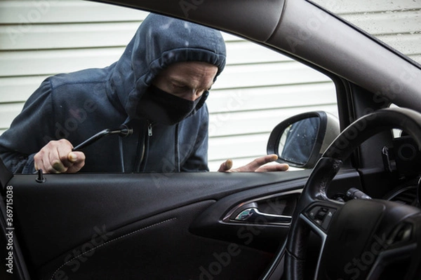 Obraz The criminal is trying to hack the car. Car thief.