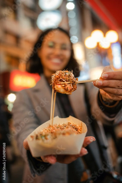 Fototapeta Mujer ofreciendo un delicioso takoyaki, tentempié tradicional de pulpo japonés