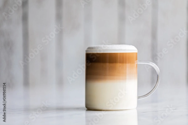 Obraz Cafe latte macchiato layered coffee in a see through glass cup on white background.