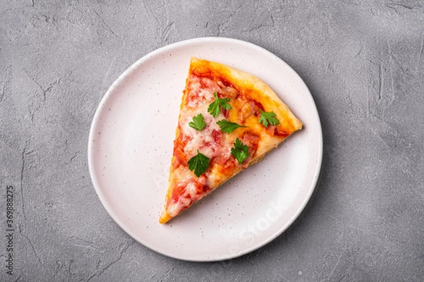 Fototapeta Hot pizza slice with mozzarella cheese, ham, tomato and parsley on plate, stone concrete background, top view
