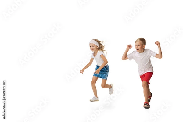 Obraz Fun. Happy kids, little emotional caucasian boy and girl jumping and running isolated on white background. Look happy, cheerful, sincere. Copyspace for ad. Childhood, education, happiness concept.