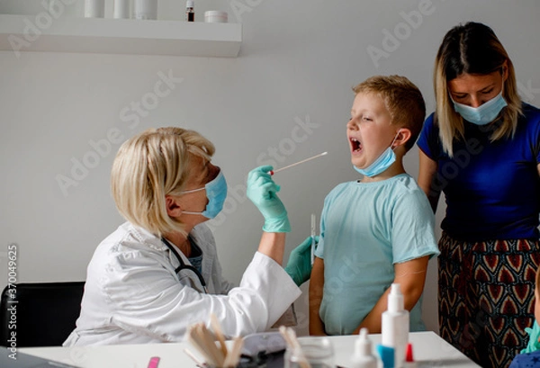 Fototapeta Doctor taking a sample from a boy's throat using a cotton swab