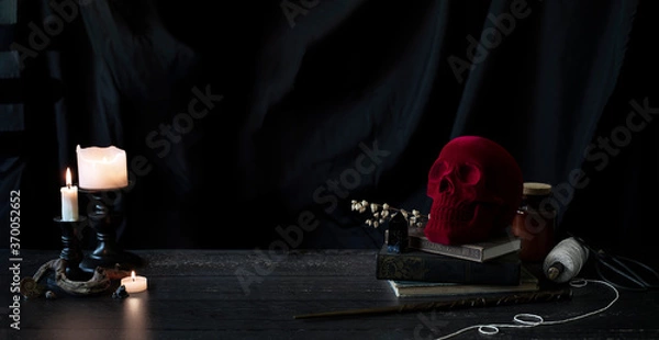 Obraz witch or wizards desk, smoking candles on library table with vintage books, magic wand and other halloween decor, and a dark background with copyspace