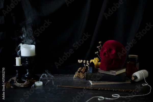 Obraz witch or wizards desk, smoking candles on library table with vintage books, magic wand and other halloween decor, and a dark background with copyspace