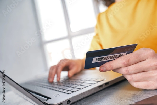 Fototapeta Close up shot of bank card in hand of woman. Shopping online from home