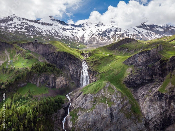 Obraz Stunning waterfall in the Swiss alps canton Berne. Aerial drone shot. Snowy mountains in the background.