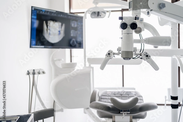 Fototapeta Interior of dental practice room with close up on microscope and dental scan on the display. Stomatology modern equipment