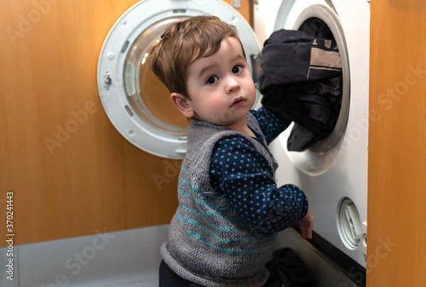 Obraz Child helping to set up the washing machine to do the laundry.