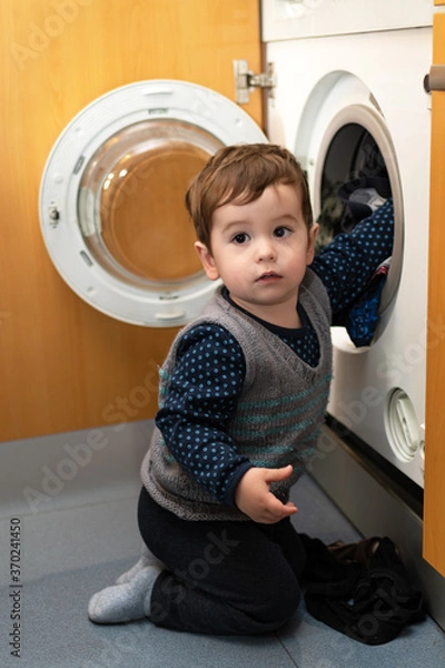 Obraz Child helping to set up the washing machine to do the laundry.