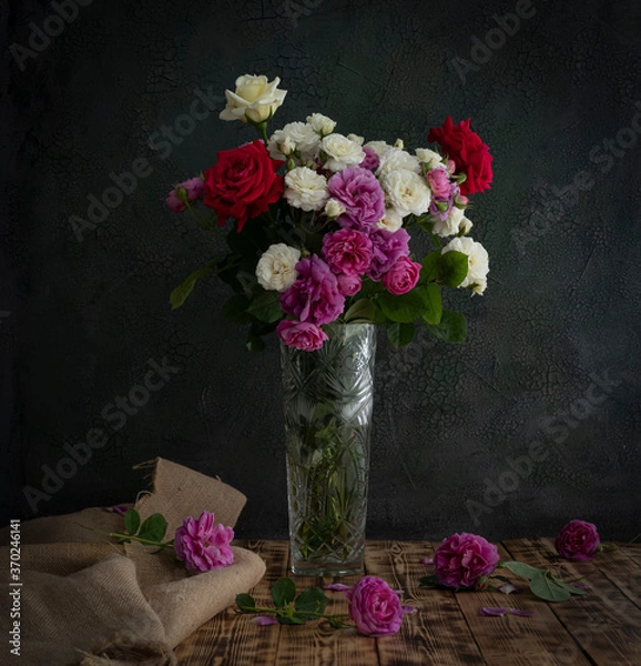 Fototapeta A bouquet of white and red roses stands in a crystal vase on a wooden table.