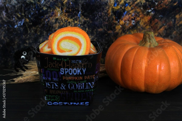 Obraz Candy corn swirl cookies in a Halloween container.  Low light