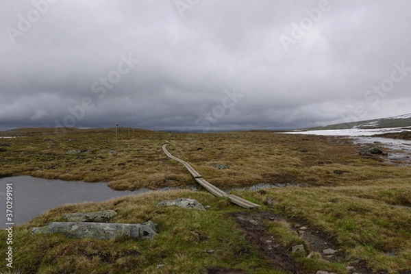Fototapeta Empty hiking trail in Swede with some dark clouds, water and some snow