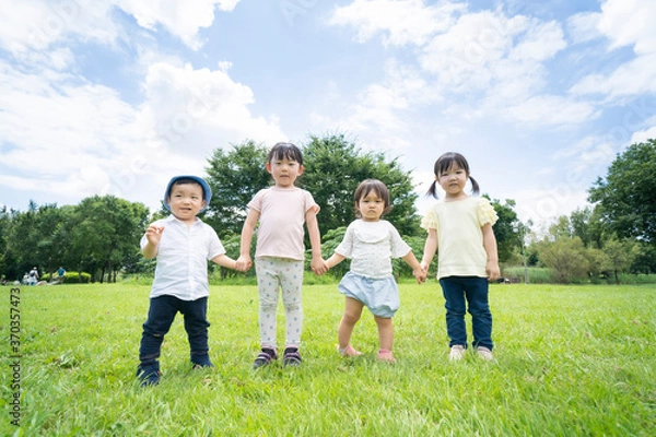 Fototapeta 青空の下、手を繋いで一列に並ぶ子供たち