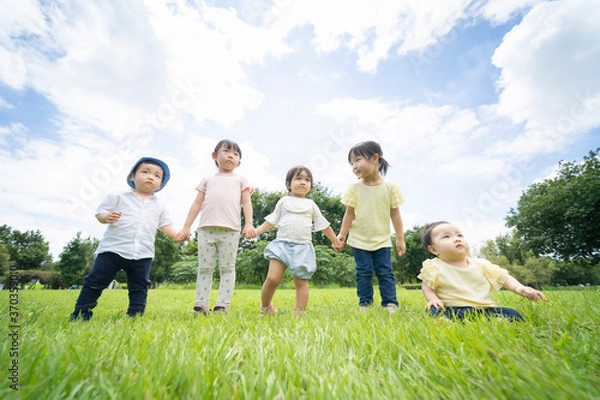 Fototapeta 青空の下、手を繋いで一列に並ぶ子供たち