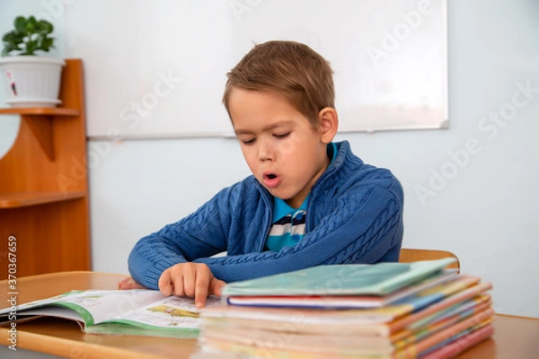 Obraz a six-year-old boy reads a book aloud