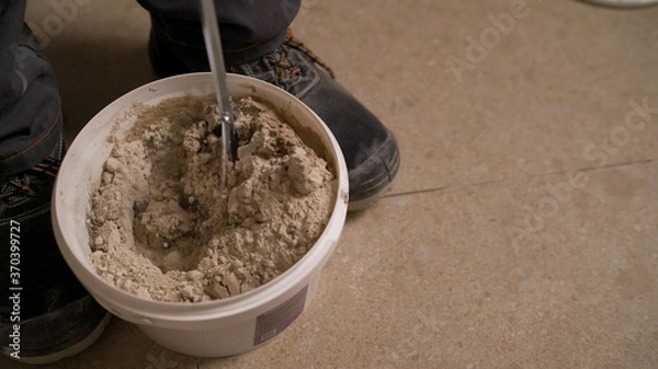 Fototapeta tile adhesive mixture in yellow bucket. Stir the tile adhesive in a bucket