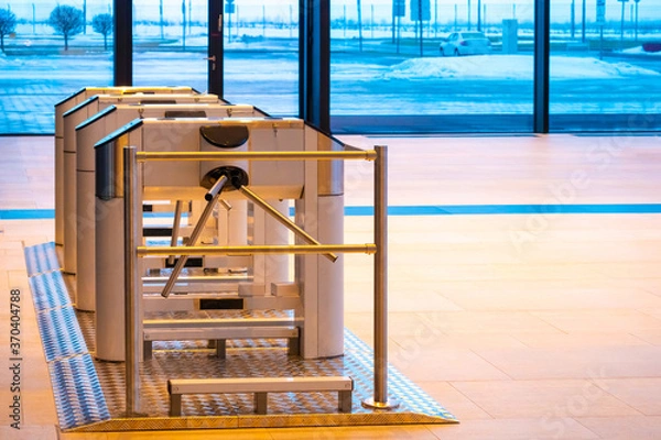 Fototapeta Turnstiles in a spacious building. Access system in an office building. Control of access to premises. Security system in the room. The entrance to the office through the turnstiles.
