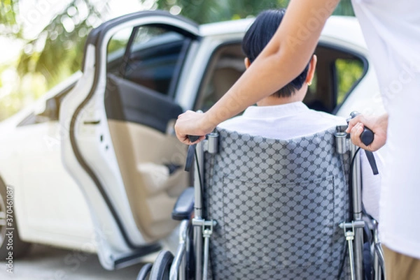 Obraz Opiekun pomaga starszym niepełnosprawnym azjatyckiej kobiecie na wózku inwalidzkim wsiąść do samochodu