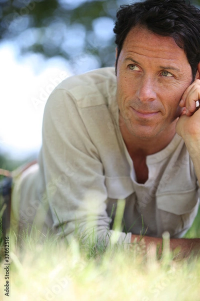 Fototapeta Man lying on the grass thinking.