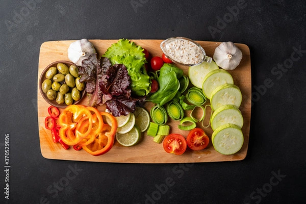 Fototapeta Background healthy food - raw tomatoes, peppers, olives, garlic on a black background, bright color, vitamin food with copy space