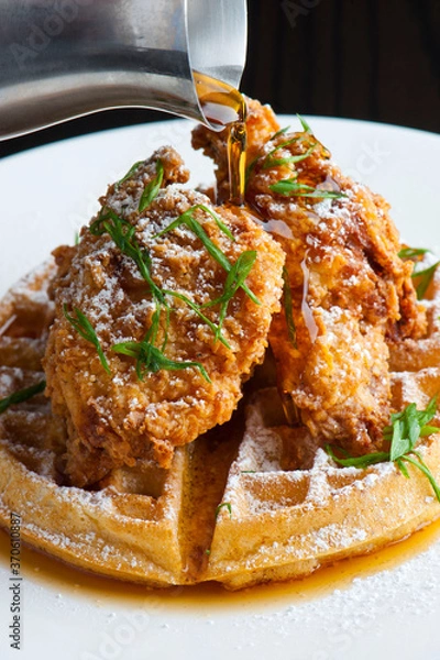 Fototapeta Chicken and waffles Classic American Diner Style Breakfast or Brunch menu item. Crispy homemade fried chicken on top of home buttermilk waffles topped with butter and maple syrup. 