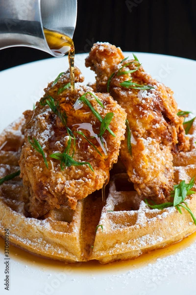 Fototapeta Chicken and waffles Classic American Diner Style Breakfast or Brunch menu item. Crispy homemade fried chicken on top of home buttermilk waffles topped with butter and maple syrup. 