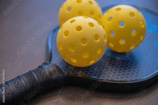 Obraz Dwie pikle. Pickleball to popularny amerykański sport, w którym gra się wiosłami i piłeczkami wiffle na korcie o wielkości 1/4 kortu tenisowego.