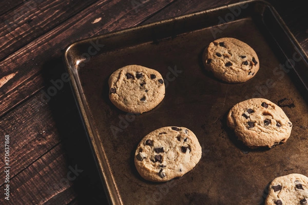 Fototapeta Fresh baked chocolate chip cookies still in the baking pan on a wooden table top.