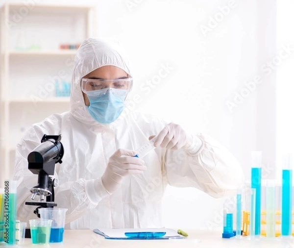 Fototapeta Young chemist student working in lab on chemicals