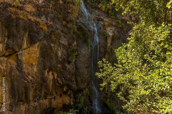 Obraz A waterfall cascades down the side of a mountain in the Sierra Nevada mountains outside Monachil, Spain in the summertime