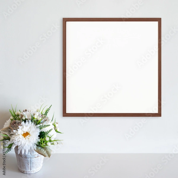 Obraz Wood frame mockup on white wall with pot of flowers on white surface. Dark wood. Copy space.