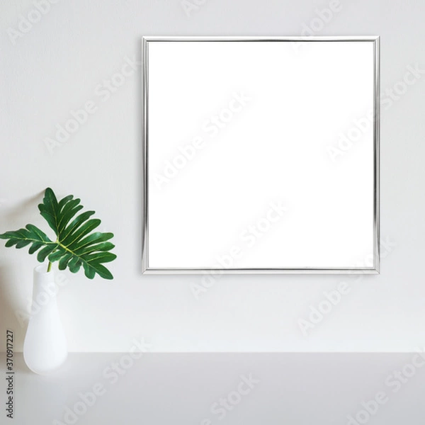 Obraz Silver frame mockup on white wall with philodendron leaf in vase on white surface. Copy space.