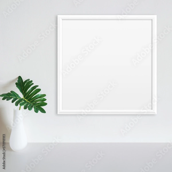 Obraz White frame mockup on white wall with philodendron leaf in vase on white surface. Copy space.
