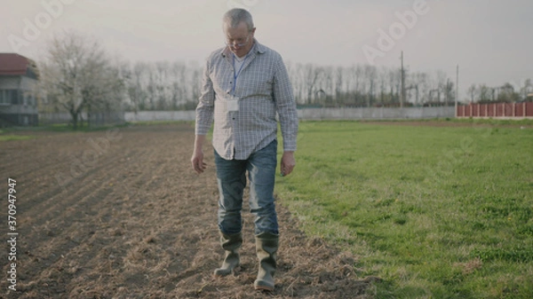 Fototapeta Portrait of a happy man farmer in nature checks the ground on field green meadow park adult agriculture garden male worker casual one person close up