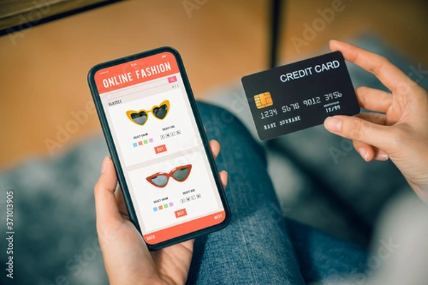 Fototapeta Hand holding smartphone and using application shopping online with payment by credit card online.