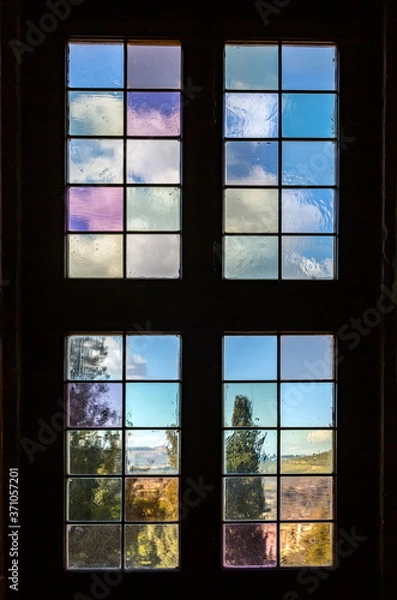 Fototapeta Old a window with multi-colored glass that overlooks a garden.