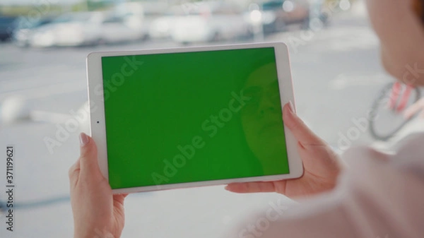 Fototapeta Close up hands woman using tablet device computer with green screen outdoors in street at sunlight horizontal bloom message pad technology chroma key female digital girl app chat finger mock up