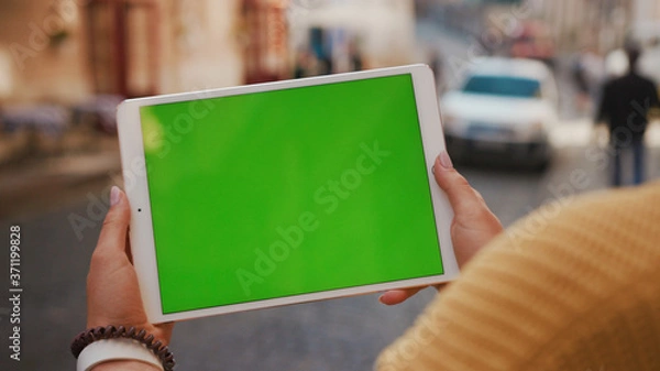 Fototapeta Close up hands woman using tablet device computer with green screen outdoors in street at sunlight horizontal bloom message pad technology chroma key female digital girl app chat finger mock up