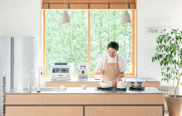 Fototapeta キッチンで料理する若い男性