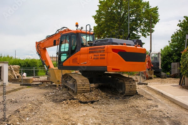 Fototapeta A crawler excavator with a rotating house platform and continuous caterpillar track on a sewer replacement work site in north west Italy
