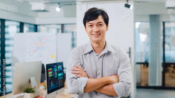 Fototapeta Portrait of successful handsome executive businessman smart casual wear looking at camera and smiling, arms crossed in modern office workplace. Young Asia guy standing in contemporary meeting room.