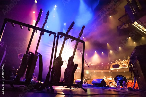 Fototapeta stojak z gitarami elektrycznymi pod oświetleniem scenicznym w teatrze