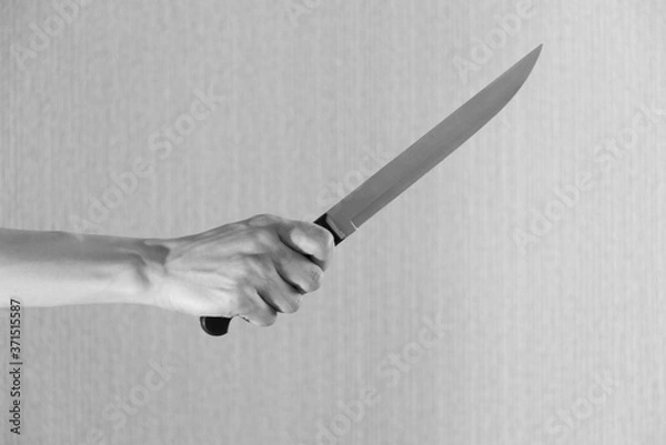 Obraz Hand is holding a kitchen kinfe isolated on a gray background